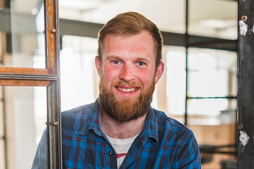 smiling-bearded-man-holding-disposable-coffee-cup-while-opening-door